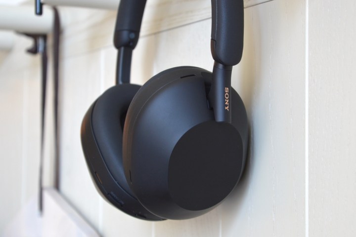 Sony WH-1000XM5 wireless headphones hanging on wall hook.